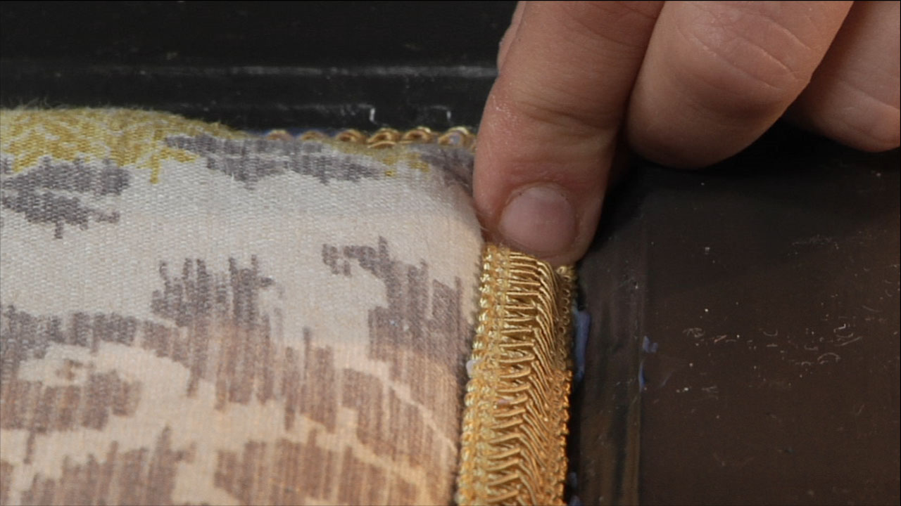 Attach the decorative fabric trim to an Upcycled Upholstered Headboard