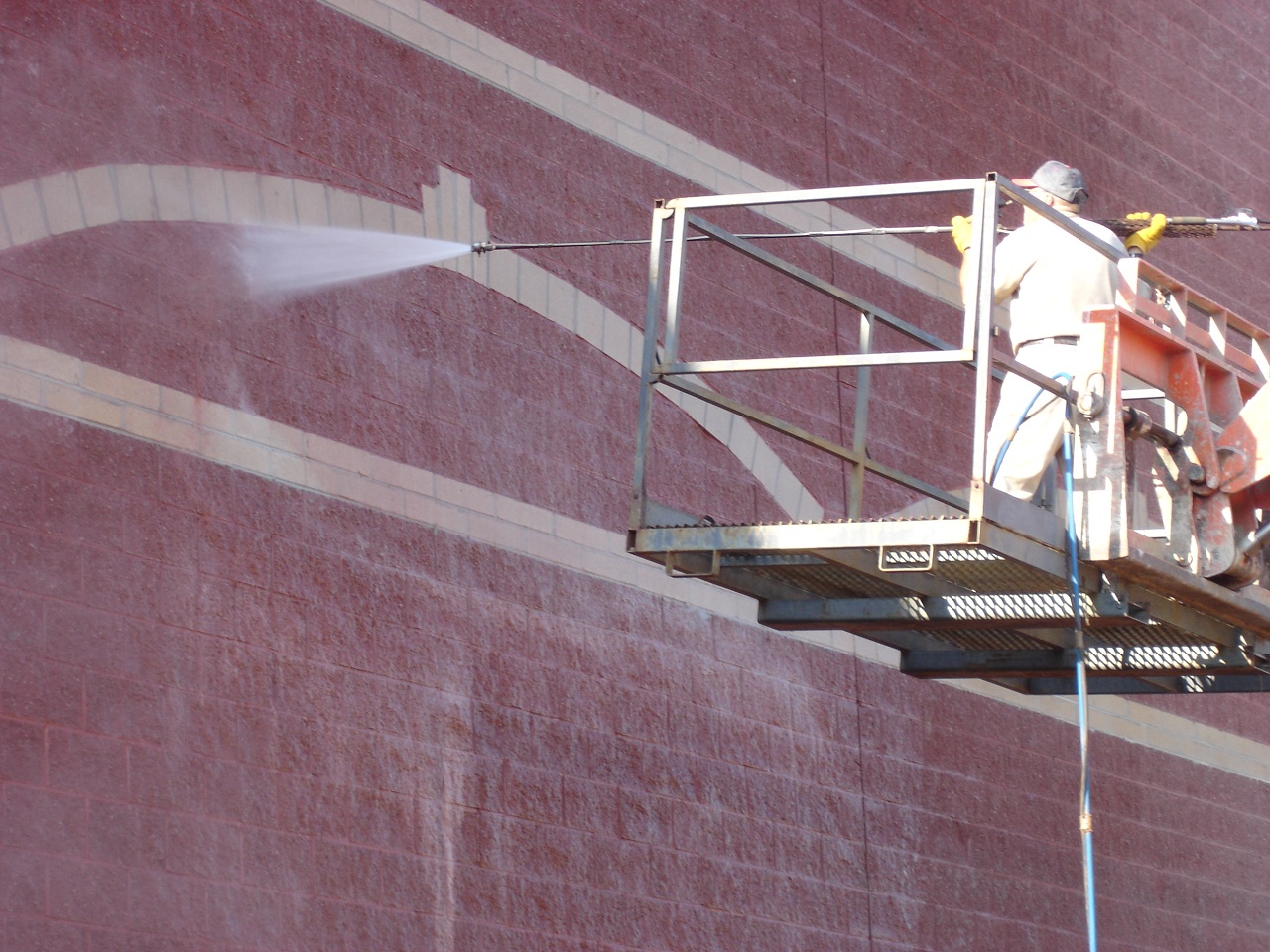 A worker washing a masonry building