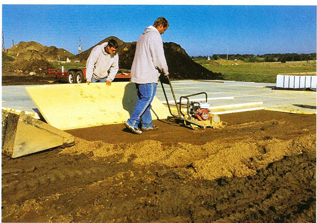Employees from Bill Eich Construction install ridged foam insulation for a garage slab.